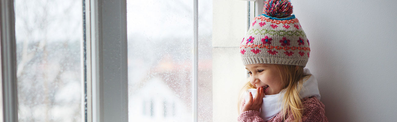 Child looking out the window at snow 