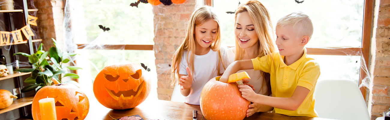 Mother and two young children making paper crafts/decorations for Halloween